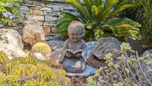 a statue of a monk reading a book in a garden at Villa Serena in La Ciotat
