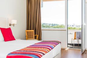 a hotel room with a bed and a large window at Hotel Londres Estoril / Cascais in Estoril