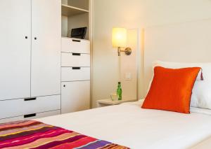 a bedroom with a white bed with an orange pillow at Hotel Londres Estoril / Cascais in Estoril
