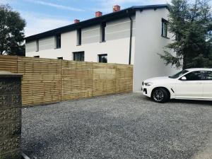 un coche blanco estacionado frente a una valla en Loft House Apartment Studio z ogródkiem 1, en Rybnik