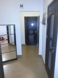 クラヨーヴァにあるDeea Apartamentの黒い扉と鏡のある廊下