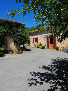 a stone building with red doors and a driveway at Holli cottage - Charming 2 bedrooms with terrace. in Saint-Avit-Rivière