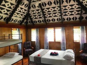 a bedroom with two beds in a room with windows at Nabua Lodge in Nacula Island