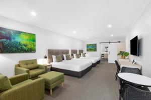 a hotel room with beds and chairs and a tv at Presidential Motel in Mount Gambier