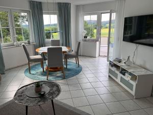 - un salon avec une table et des chaises dans l'établissement Ferienwohnung-Orth-Tor-zum-Sauerland-mit-grosser-Terrasse, à Meinerzhagen