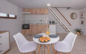 a kitchen with a white table and white chairs at Cozy Loft with Private Terrace in Kremasti