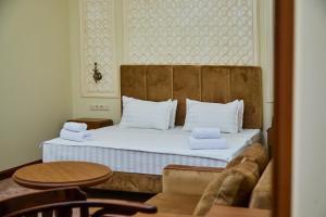 um quarto com uma cama com almofadas brancas e uma mesa em Sangzor Boutique Hotel em Samarkand