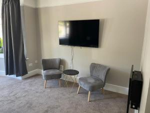 uma sala de estar com duas cadeiras e uma televisão na parede em Bayside GuestHouse em Bournemouth