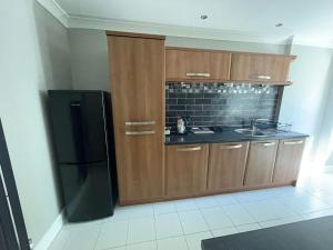 cocina con armarios de madera y nevera negra en Bayside GuestHouse en Bournemouth