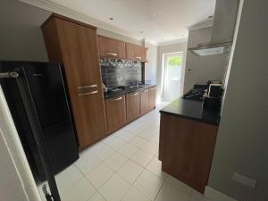 a kitchen with wooden cabinets and a black refrigerator at Bayside GuestHouse in Bournemouth