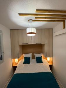 um quarto com uma cama grande e 2 almofadas azuis em Appart en résidence calme avec parking privé em Leucate