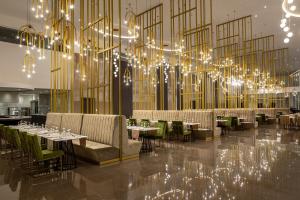 a restaurant with tables and chairs and a large chandelier at Chrysomare Beach Hotel & Resort in Ayia Napa