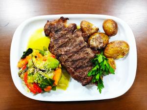 a plate of steak and potatoes on a table at Hotel Império do Norte in Ponte de Lima