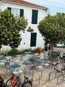 a group of chairs and tables with bikes in front of a building at Chambre d'hôtes Hôte des Portes Île de Ré in Les Portes