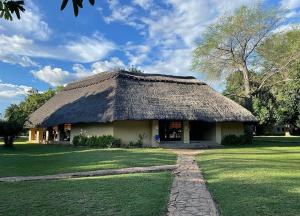 a hut with a grass roof on a field at Marula Lodge in Mfuwe