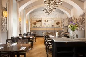 un restaurante con mesas y sillas y una lámpara de araña en The Hotel Fitzgerald, en Praga