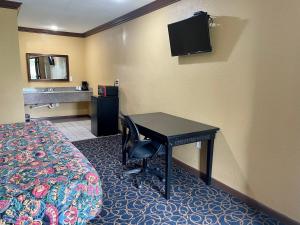 a hotel room with a desk with a bed and a sink at Super 6 Inn in Carencro +4 photos