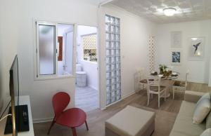 ein weißes Wohnzimmer mit einem roten Stuhl und einem Tisch in der Unterkunft Luisan Guanarteme in Las Palmas de Gran Canaria