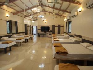 a room with a row of beds and a tv at Cocorico Beach Resort in Dapoli