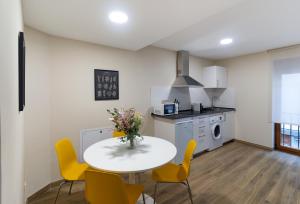 a kitchen with a white table and yellow chairs at Housing León Azabachería 1A, 1B, 2A, 2B in León +34 photos