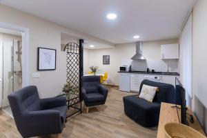 a living room with two chairs and a couch and a kitchen at Housing León Azabachería 1A, 1B, 2A, 2B in León