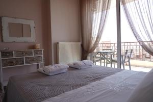 a bedroom with a bed and a balcony with a table at Blue Jasmine in Aigio