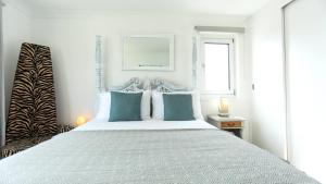 um quarto branco com uma cama grande e almofadas azuis em Tides - Beach front apartment in Bracklesham Bay em Chichester