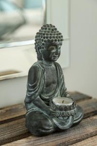 a statue of a buddha holding a bowl at Tides - Beach front apartment in Bracklesham Bay in Chichester +23 photos