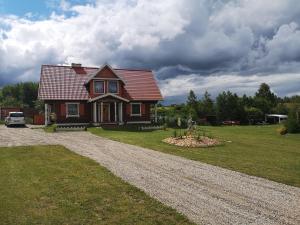 a house on a gravel road in front of a yard at Duży dom i domki z bala Mikołajki - Całoroczne in Mikołajki