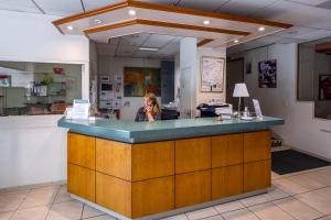 a woman talking on a cell phone at a counter at Noemys Brive - ex Hôtel Restaurant Le Teinchurier in Brive-la-Gaillarde