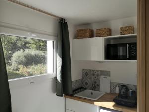 a kitchen with a window and a sink and a microwave at Studio au calme vue sur garlaban in Roquevaire