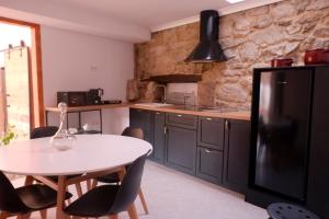 Sas de Penelas的住宿－A casa da Penela，厨房配有白色桌子和黑色冰箱。