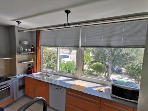 eine Küche mit einem großen Fenster mit Jalousien in der Unterkunft Le coteau fleuri in Carnoux