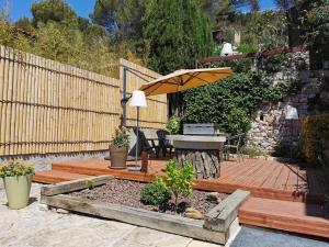 una terrazza in legno con tavolo e ombrellone di Le coteau fleuri a Carnoux
