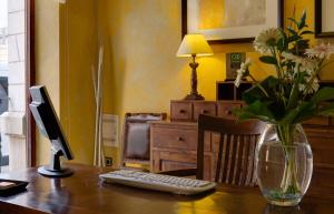 a desk with a computer monitor and a vase of flowers at L'Agora Hotel in Bocairent