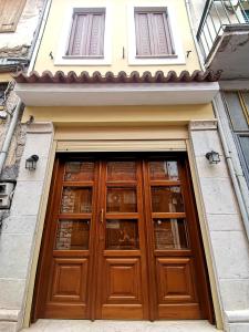 uma porta de madeira num edifício com duas janelas em Ξενώνας Λήδα em Andrítsaina