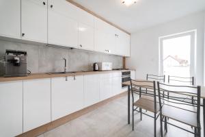 a kitchen with white cabinets and a table and chairs at WODA I WIATR PL Wiatrakowa 26 Jastrzębia Góra in Jastrzębia Góra