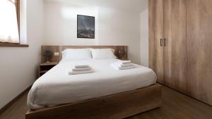 una camera da letto con un grande letto con lenzuola bianche di Italianway - Ciuk 11 a Bormio