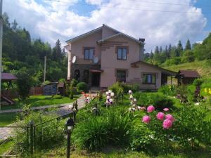 ein Haus auf einem Hügel mit Blumen im Hof in der Unterkunft Бодрість карпат in Slawske