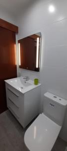 een witte badkamer met een wastafel en een spiegel bij Sunny studio Flat in Los Cristianos