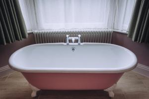a bath tub in a bathroom with a window at The Drummond at Albury in Guildford
