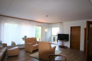 sala de estar con sofá, sillas y TV en Ferienwohnung Zum Rosengarten WEST015 Westerwald, en Driedorf