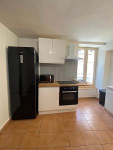 cocina con nevera negra y armarios blancos en L'appartement ZEN LOC 2, en Bray-sur-Seine