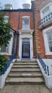 a blue door on a brick building with stairs at Cruden Villa - Second Floor Apartment in Scarborough