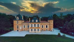 a large mansion with a sunset in the background at Château Bois-Martin in Léognan