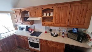 a kitchen with wooden cabinets and a stove top oven at Cruden Villa - Second Floor Apartment in Scarborough