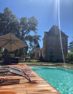 a swimming pool with an umbrella and a house at Château Bois-Martin in Léognan