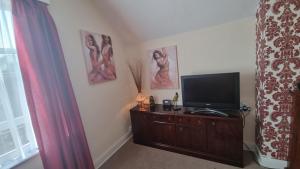 a living room with a television on a wooden dresser at Cruden Villa - Second Floor Apartment in Scarborough