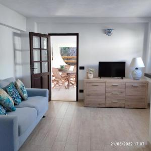 un soggiorno con divano blu e TV di Villa Su Giudeu a Chia