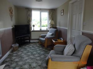 a living room with two chairs and a television at Sterling Bed & Breakfast in Llandudno